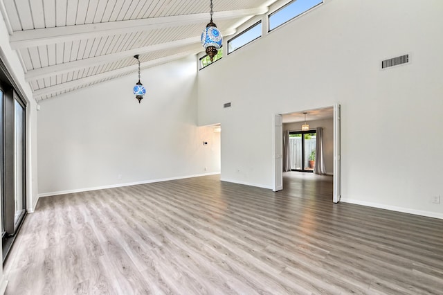 unfurnished living room featuring a towering ceiling, hardwood / wood-style floors, and beamed ceiling