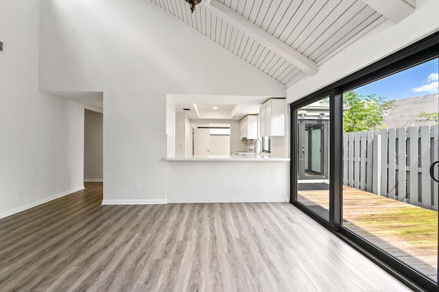 unfurnished living room with beam ceiling and light wood-type flooring