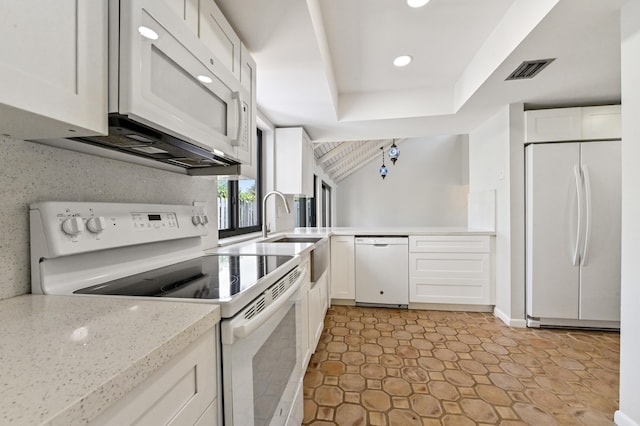 kitchen featuring white appliances, white cabinets, decorative backsplash, sink, and a tray ceiling