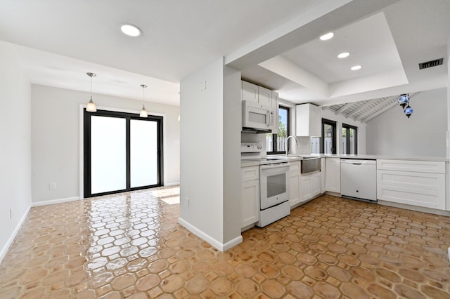 kitchen with a raised ceiling, white appliances, pendant lighting, white cabinets, and sink