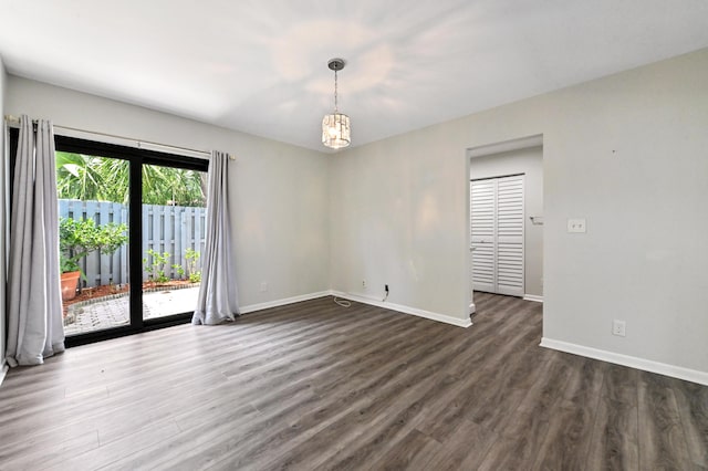 spare room featuring a chandelier and dark hardwood / wood-style flooring