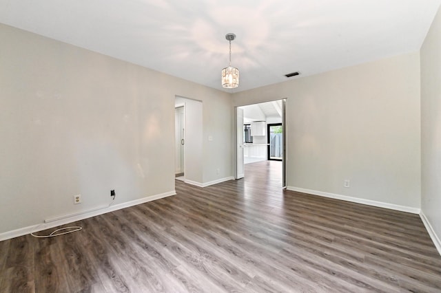 spare room featuring dark hardwood / wood-style floors and an inviting chandelier