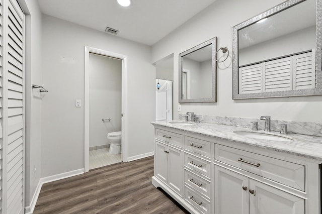 bathroom featuring toilet, wood-type flooring, and vanity