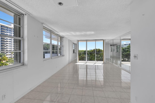 tiled spare room featuring floor to ceiling windows and a textured ceiling