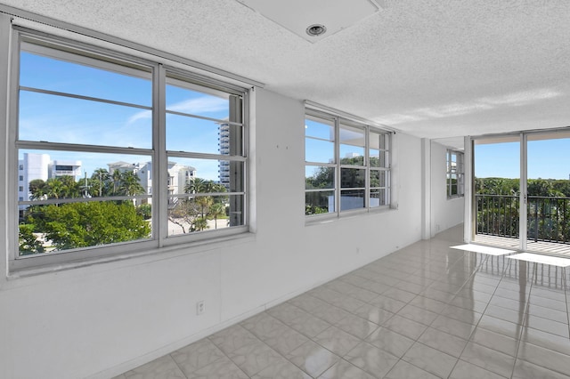 tiled empty room featuring a textured ceiling