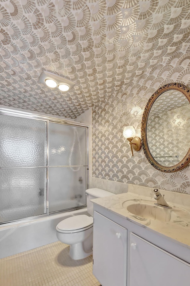 full bathroom featuring bath / shower combo with glass door, vanity, tile patterned floors, and toilet