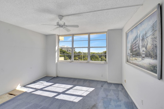 empty room with ceiling fan, light colored carpet, and a textured ceiling