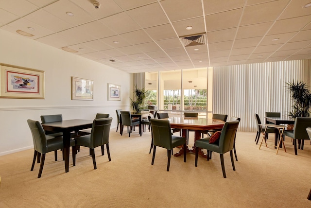 dining space featuring light carpet and a drop ceiling