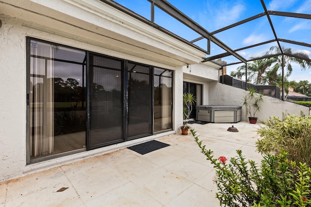 view of patio / terrace featuring a hot tub and glass enclosure