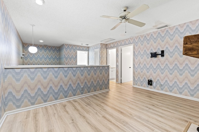 empty room featuring a textured ceiling, ceiling fan, and light wood-type flooring