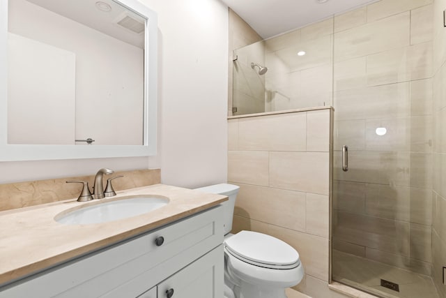 bathroom featuring toilet, vanity, and a shower with shower door