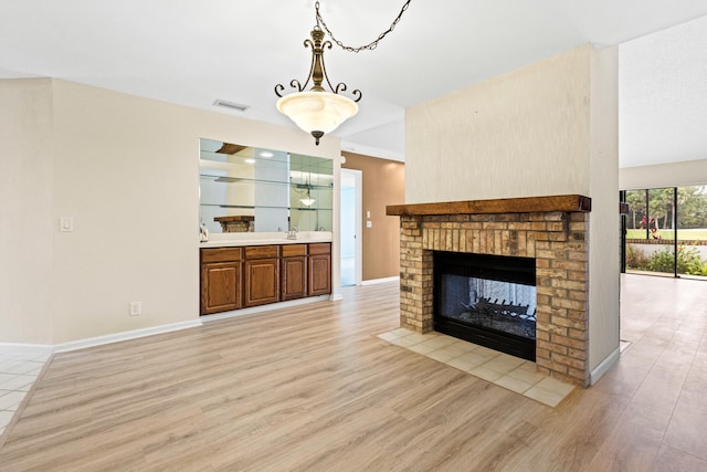 unfurnished living room featuring a fireplace, light hardwood / wood-style floors, and sink