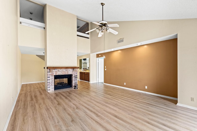 unfurnished living room with ceiling fan, light hardwood / wood-style floors, a brick fireplace, and high vaulted ceiling