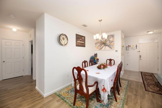 dining area featuring wood-type flooring and an inviting chandelier