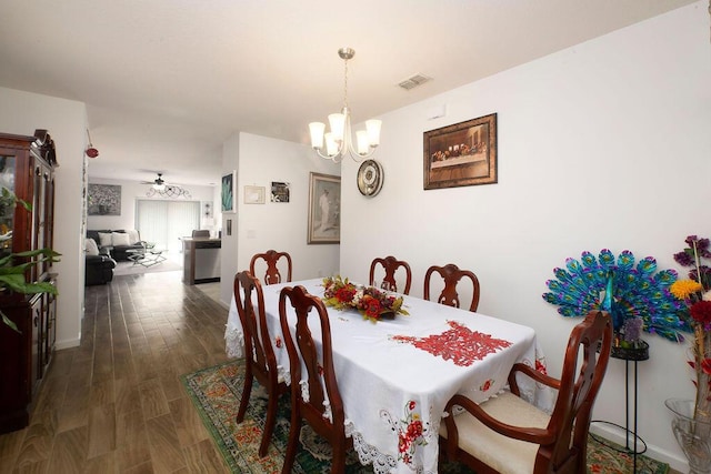 dining space featuring dark hardwood / wood-style flooring and ceiling fan with notable chandelier