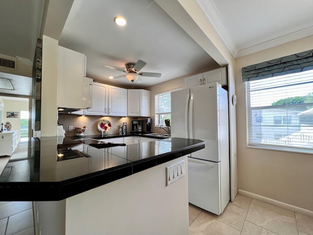 kitchen with crown molding, white refrigerator, tasteful backsplash, white cabinets, and kitchen peninsula