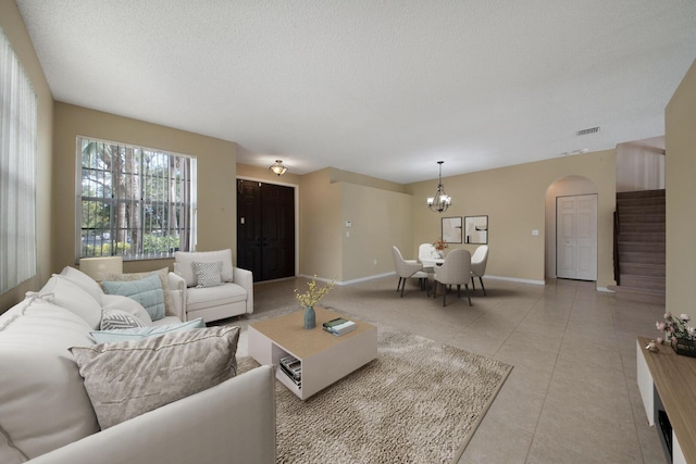 living room with an inviting chandelier, a textured ceiling, and light tile patterned floors