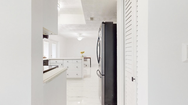 kitchen featuring a textured ceiling, white cabinetry, and stainless steel fridge