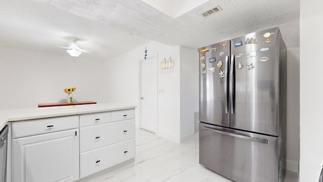 kitchen with ceiling fan, white cabinets, stainless steel appliances, and a textured ceiling