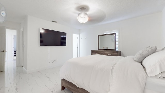 bedroom with ceiling fan and a textured ceiling