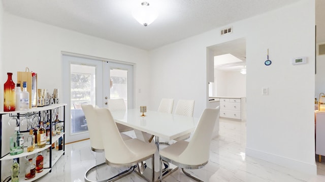 dining space with french doors and a textured ceiling