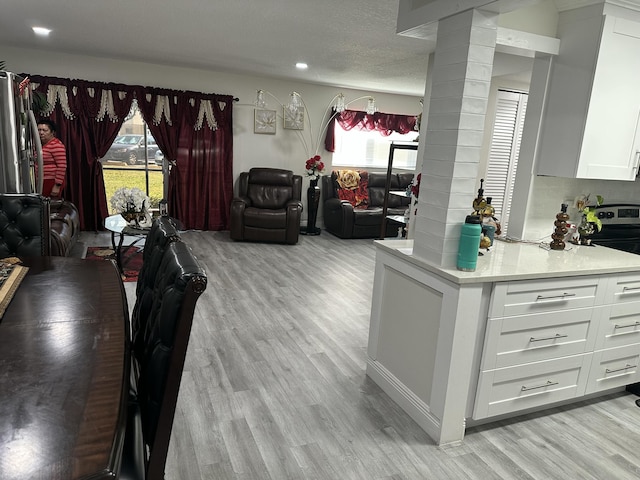 interior space with decorative columns, a textured ceiling, and light wood-type flooring