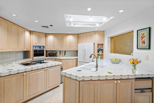 kitchen featuring decorative backsplash, appliances with stainless steel finishes, sink, and light brown cabinets