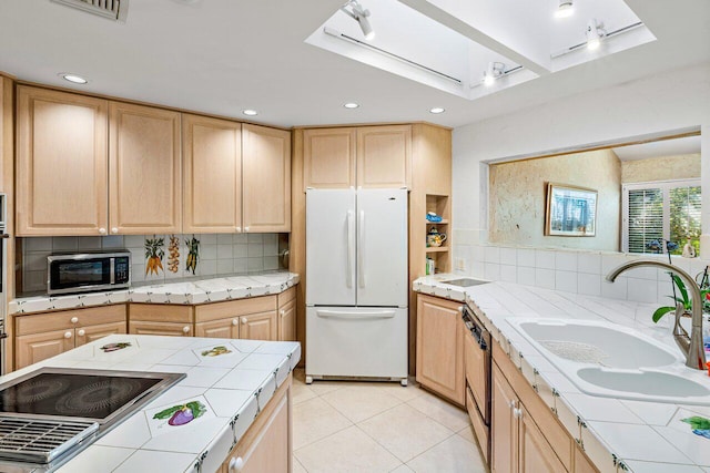 kitchen featuring backsplash, tile countertops, stovetop, and white fridge