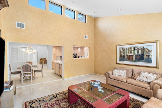 living room featuring light wood-type flooring, a towering ceiling, and a notable chandelier