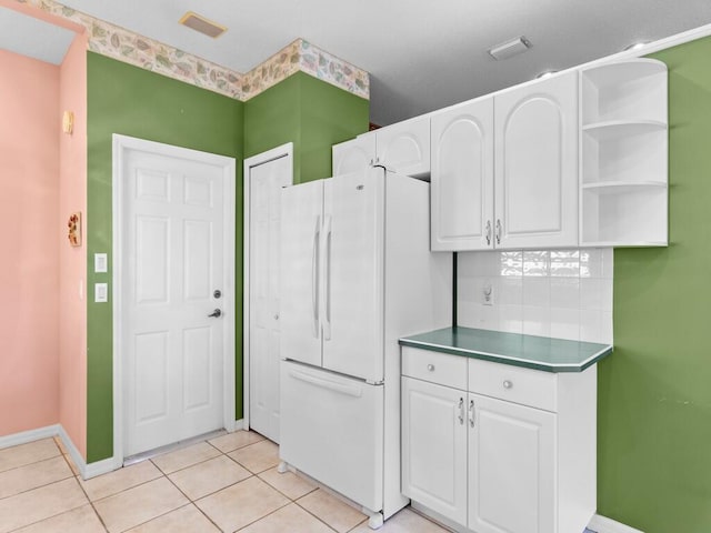 kitchen featuring light tile patterned floors, white refrigerator, white cabinets, and tasteful backsplash