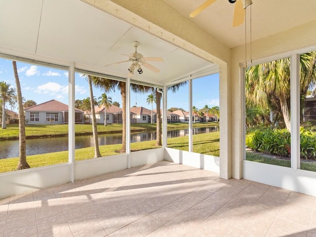 unfurnished sunroom with ceiling fan, a water view, and a healthy amount of sunlight