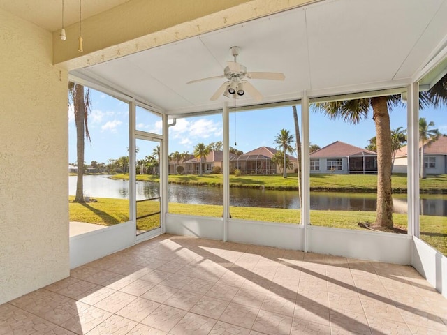 unfurnished sunroom with ceiling fan and a water view