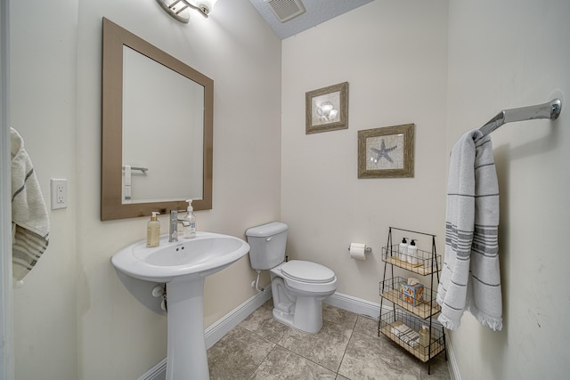 bathroom featuring toilet, tile patterned flooring, and a textured ceiling