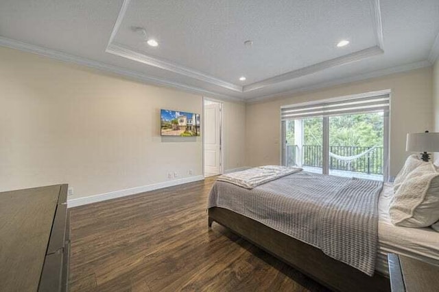 bedroom featuring a textured ceiling, dark wood-type flooring, ornamental molding, and a tray ceiling