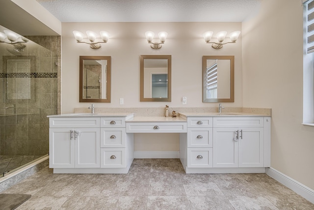 bathroom featuring a textured ceiling, vanity, and a tile shower