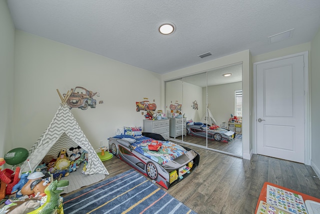 bedroom with a textured ceiling, a closet, and dark hardwood / wood-style flooring