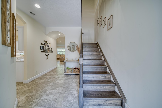 stairs with a textured ceiling