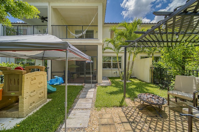 exterior space featuring a balcony, a sunroom, a fire pit, and a lawn