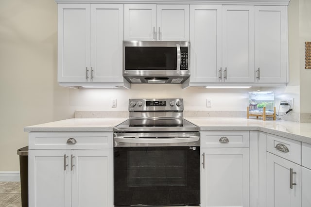 kitchen with white cabinets, light stone counters, and stainless steel appliances