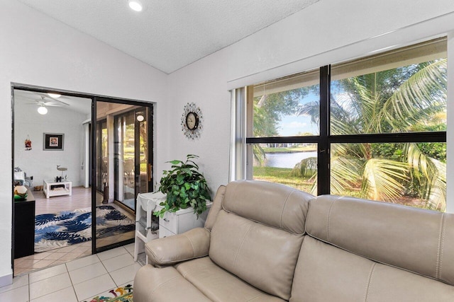 living room featuring a water view, vaulted ceiling, a textured ceiling, and light tile patterned floors