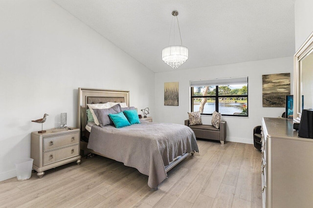 bedroom featuring light hardwood / wood-style flooring, a notable chandelier, and vaulted ceiling