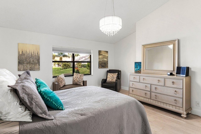 bedroom featuring lofted ceiling, a notable chandelier, and light wood-type flooring