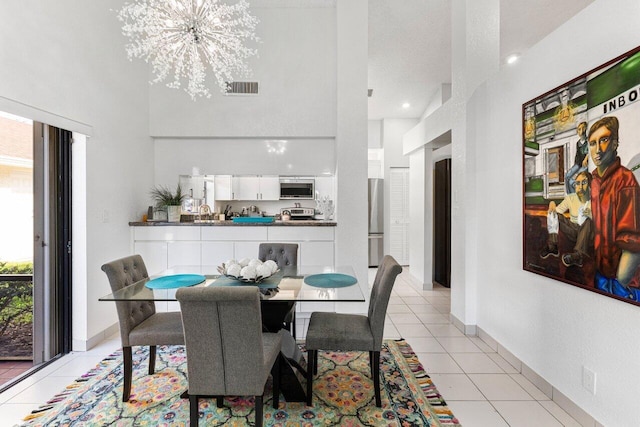 tiled dining area with an inviting chandelier and a high ceiling