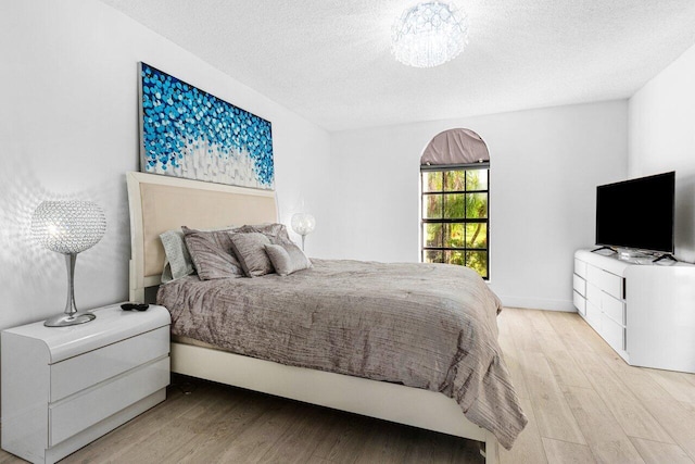 bedroom featuring a textured ceiling and light hardwood / wood-style flooring