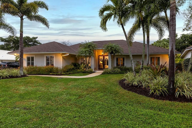 ranch-style home featuring a front lawn and stucco siding