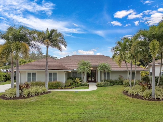 view of front facade featuring stucco siding, a front lawn, and a tiled roof