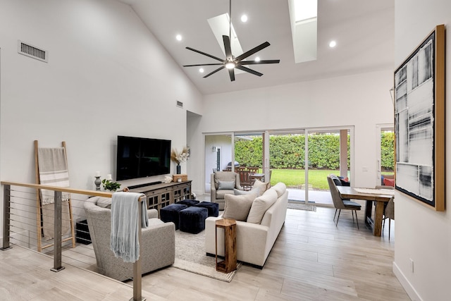 living room with ceiling fan, high vaulted ceiling, and light hardwood / wood-style flooring