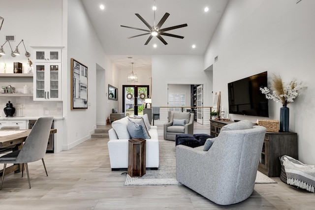 living room featuring ceiling fan with notable chandelier, high vaulted ceiling, and french doors