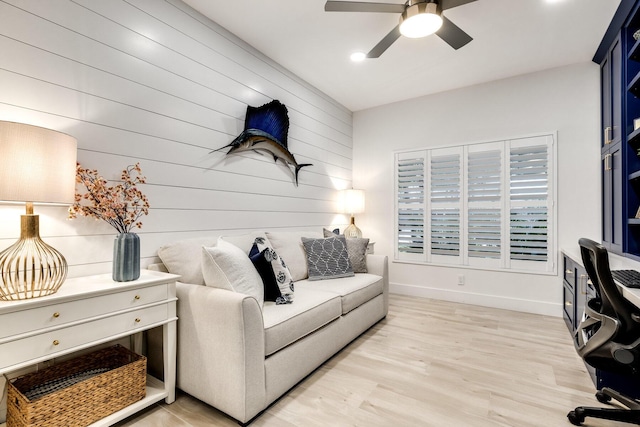 living room featuring wood walls, ceiling fan, and light hardwood / wood-style flooring