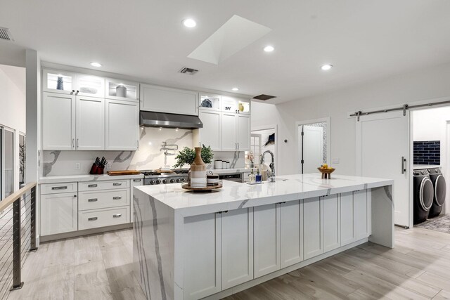 kitchen with white cabinetry, sink, stainless steel fridge with ice dispenser, and a center island with sink